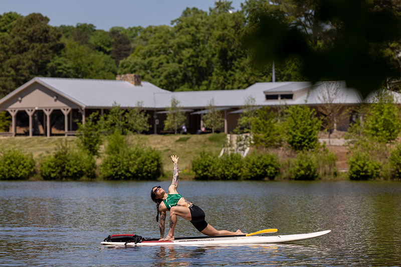 A student doing yoga on a paddleboard at Lake Herrick.
